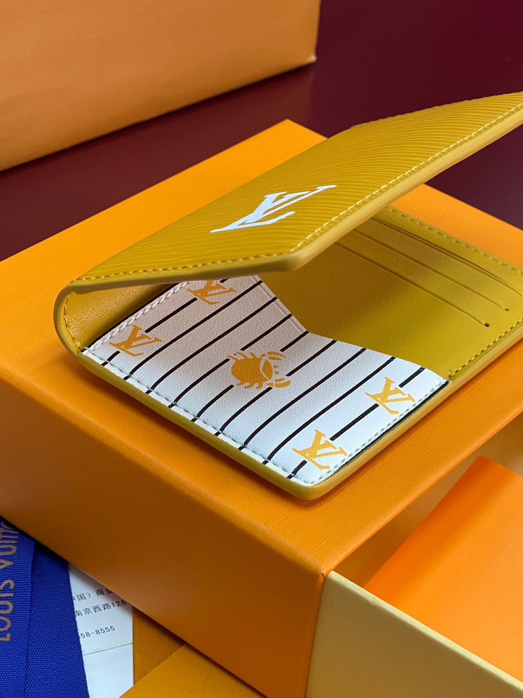 Yellow leather card holder open, striped lining with bee motif and card slots