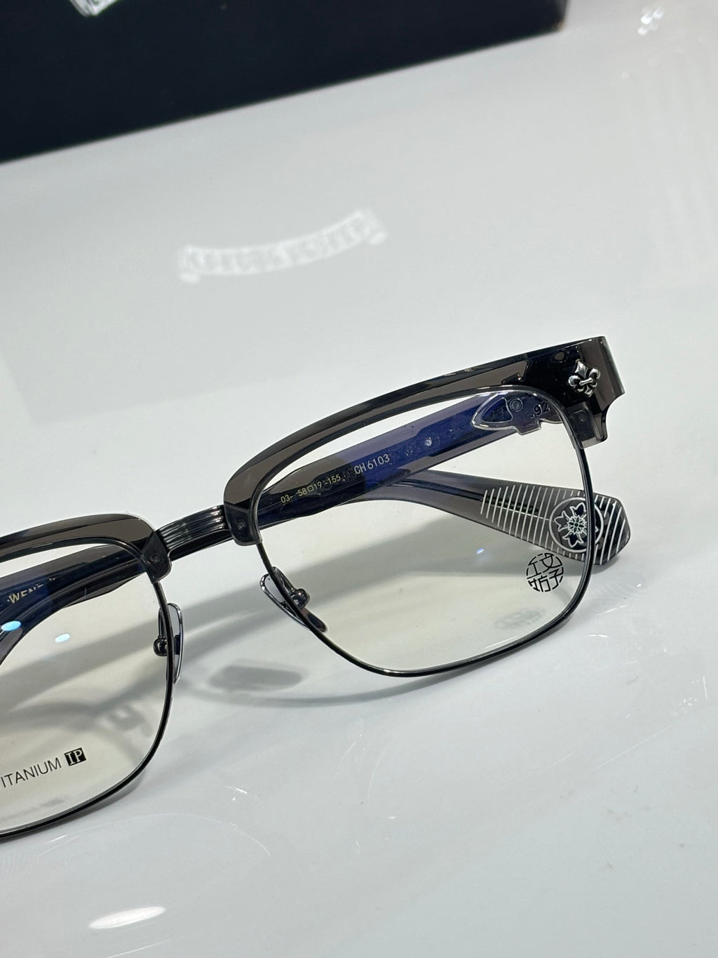Chrome glasses close-up, black frame with clear lenses and blue temple detail