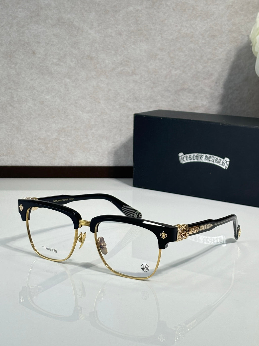Chrome glasses, black with gold-tone accents, clear lenses
