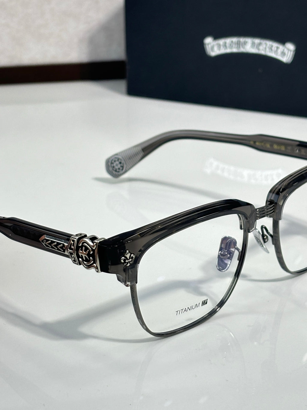 Chrome glasses side view, black frames with emblem detail and clear lenses
