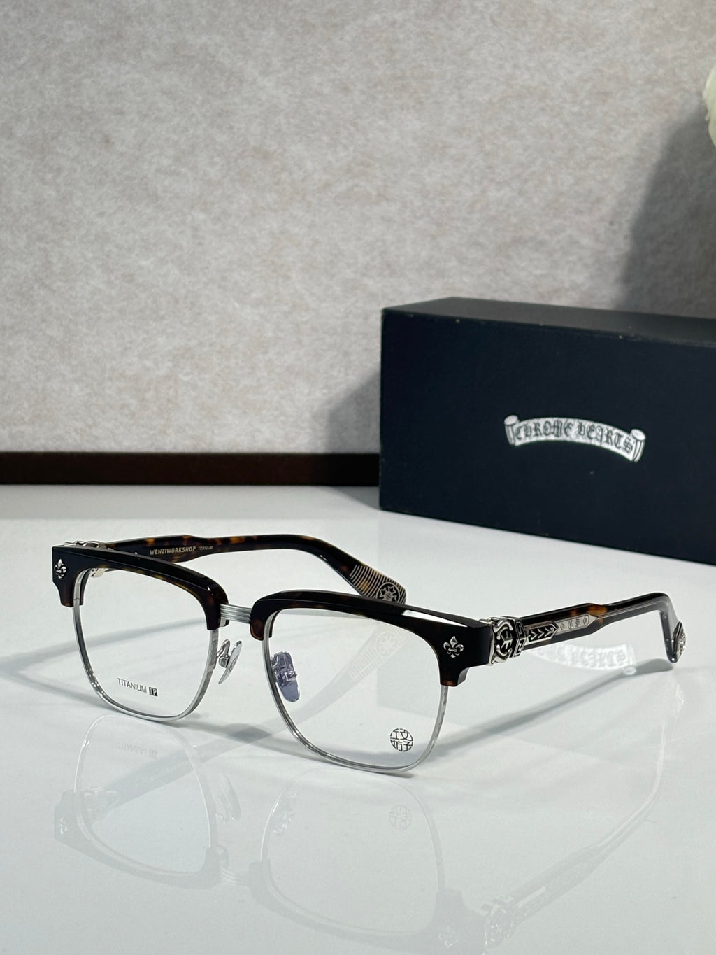 Chrome glasses, black frames with gold-tone detailing, clear lenses