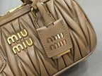 Taupe quilted leather bag detail with two front Miu Miu logo plaques and stitching