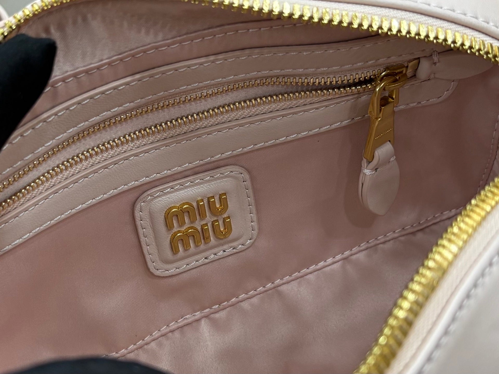 MiuMiu light gray mini bag with front interior logo patch and gold zipper pull