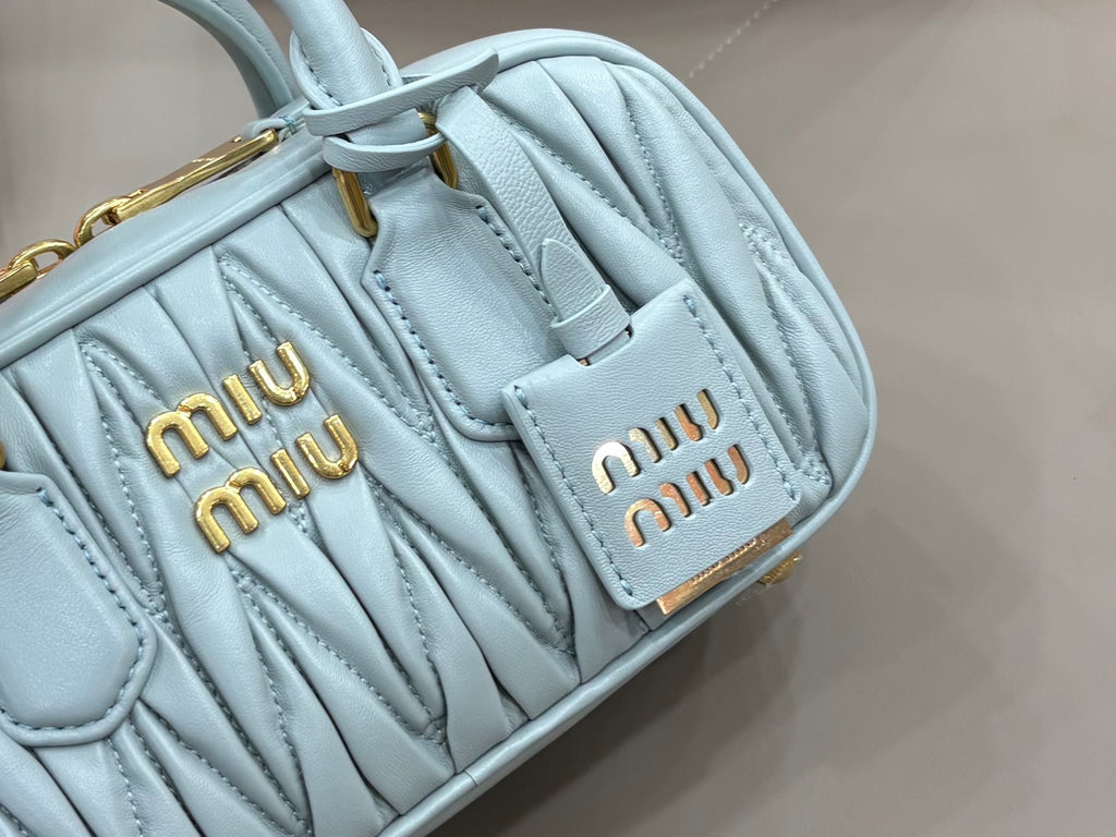 MiuMiu light blue quilted mini bag close-up of logo patch and stitched texture