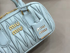 MiuMiu light blue quilted mini bag close-up of logo patch and stitched texture