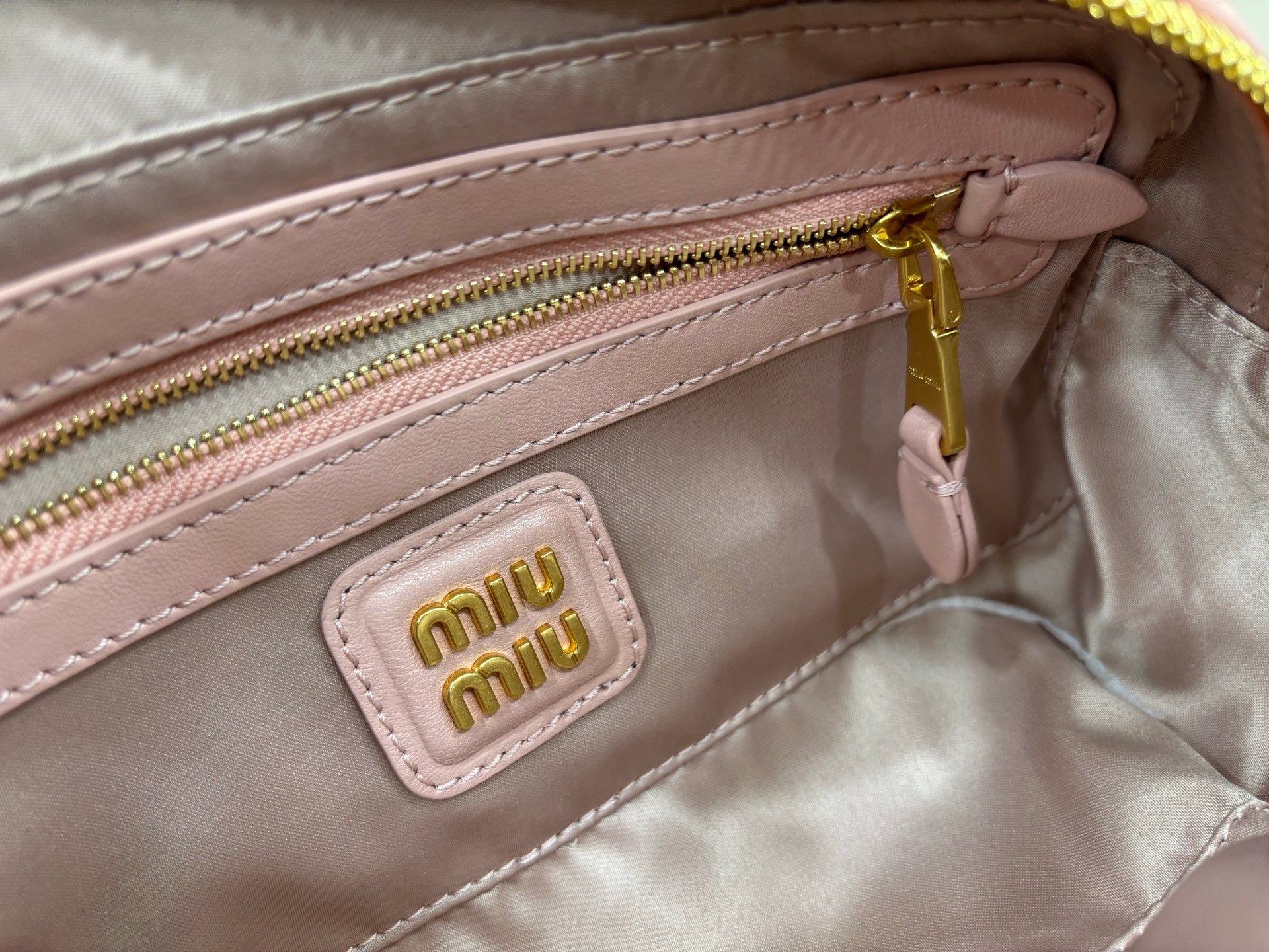 Miu Miu light pink inner pocket with logo patch and gold zipper close-up