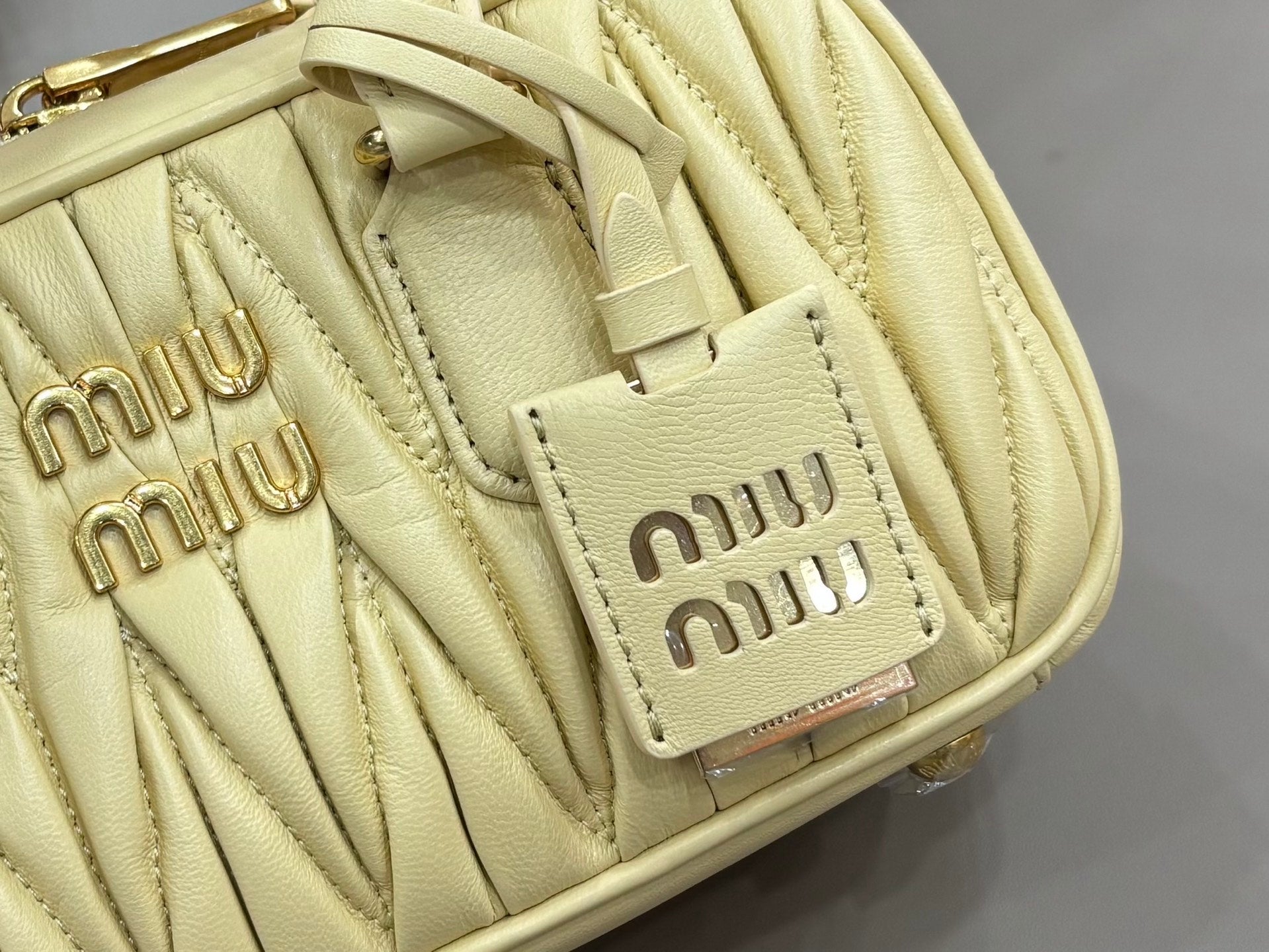 Light yellow Miu Miu quilted bag detail with front patch logo and stitching
