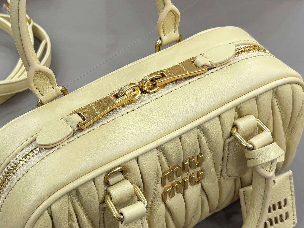 Light yellow Miu Miu bag with top zipper track and gold clasp hardware detail