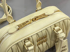 Light yellow Miu Miu bag with top zipper track and gold clasp hardware detail