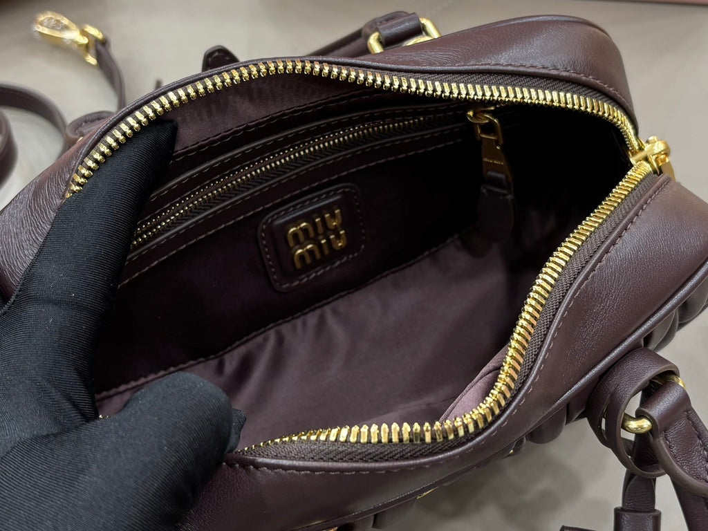 Dark brown top-handle bag interior open, showing logo patch and zip lining