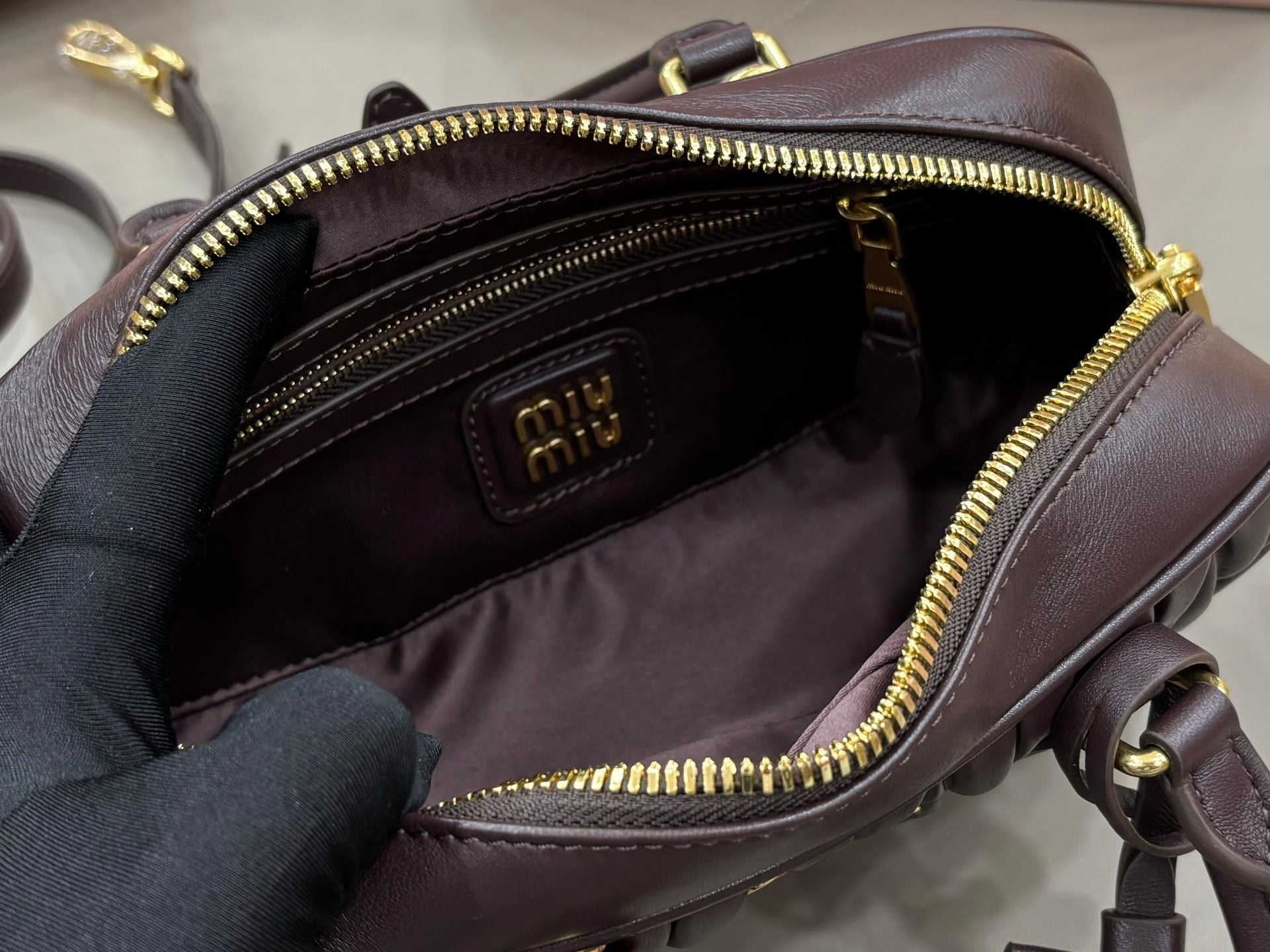 Dark brown top-handle bag interior open, showing logo patch and zip lining