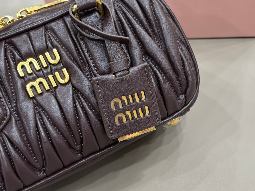 Dark brown quilted bag front close-up with two logo patches and gold hardware