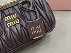 Dark brown quilted bag front close-up with two logo patches and gold hardware