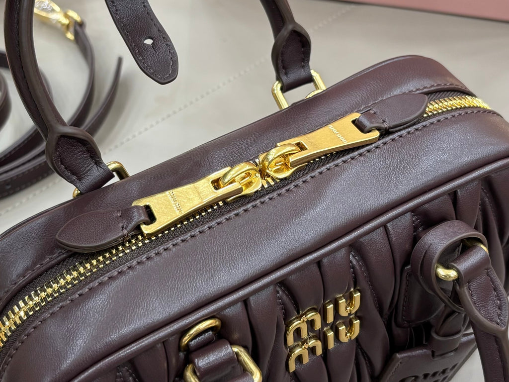 Dark brown mini top-handle bag close-up with gold zipper pull and logo