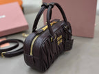 Dark brown quilted top-handle bag side view with zip pocket and gold hardware