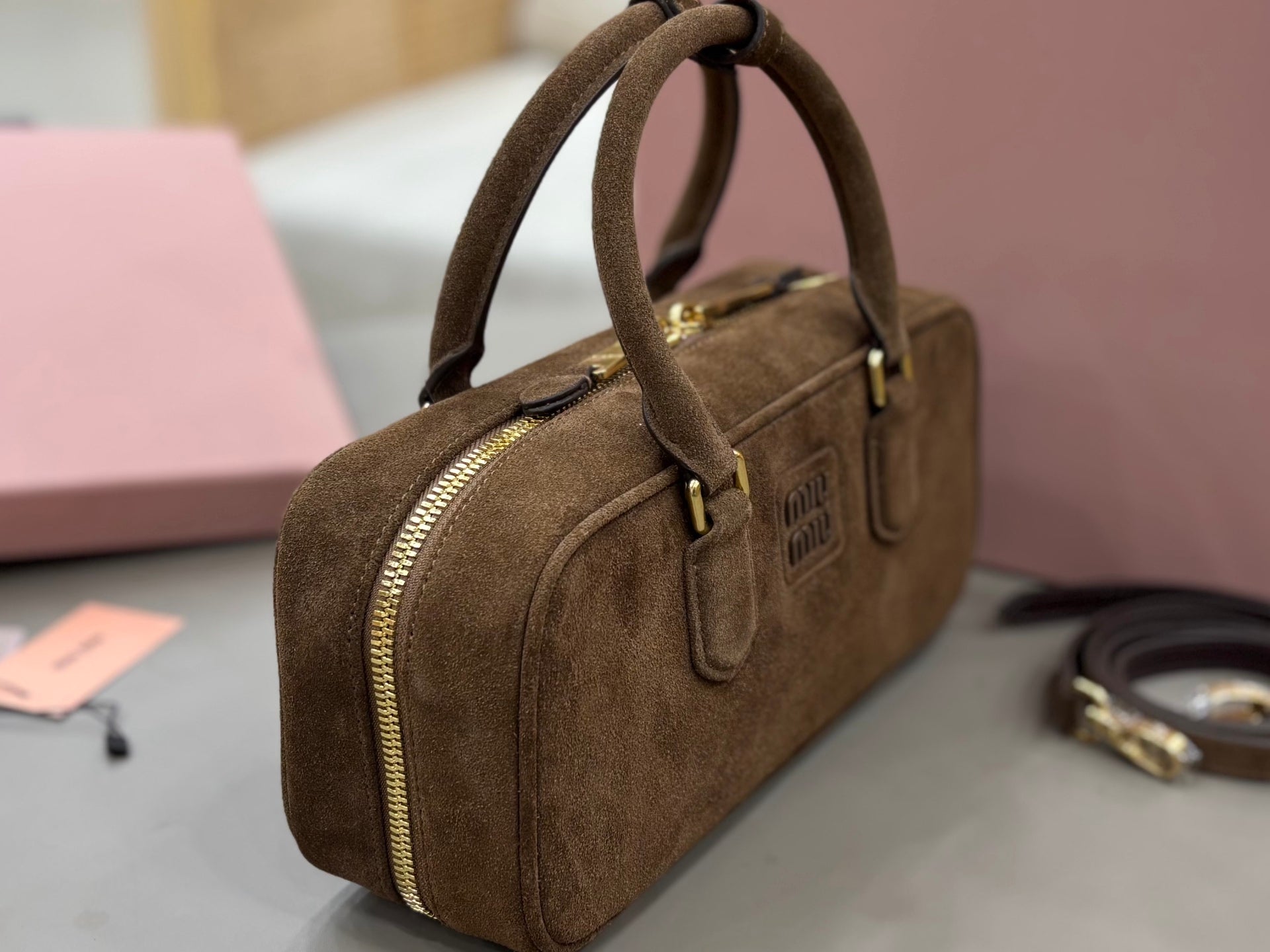 Suede mini bag with gold-tone side zipper, top handle, and front logo patch