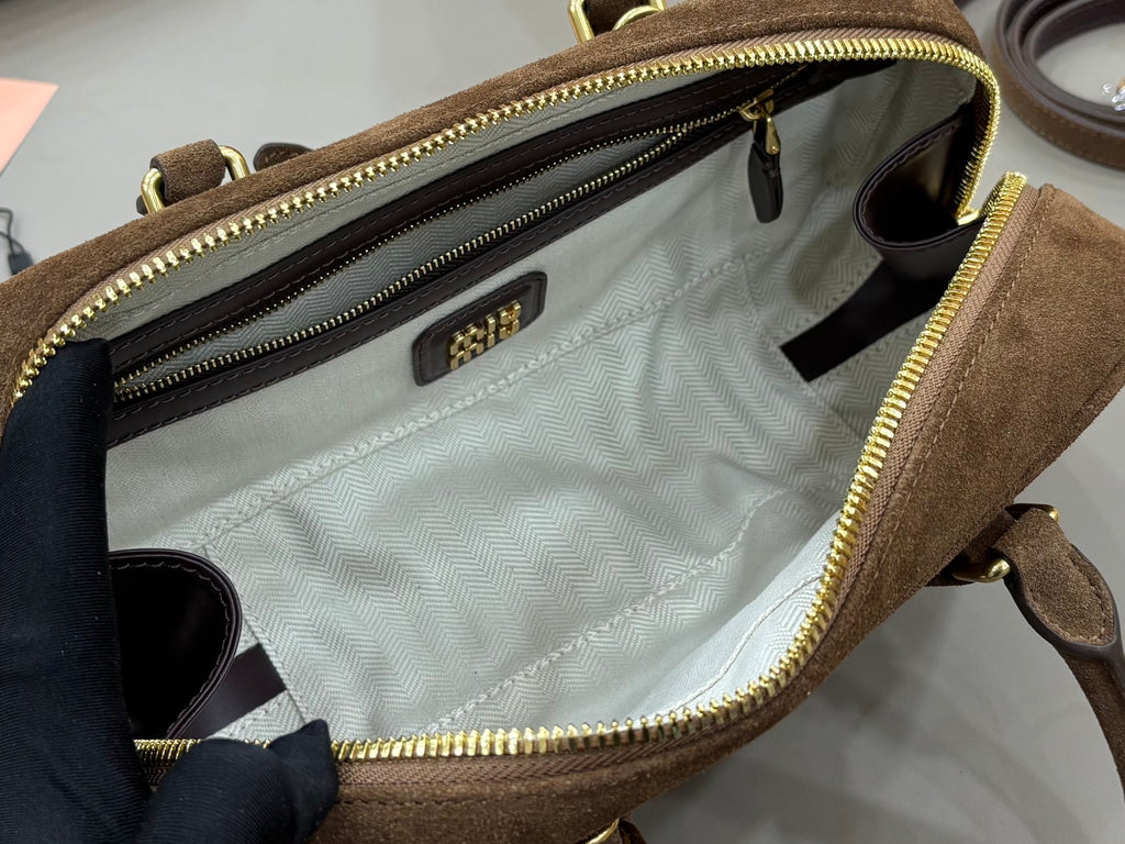 Open suede mini bag interior with chevron lining, multiple zip compartments, and label