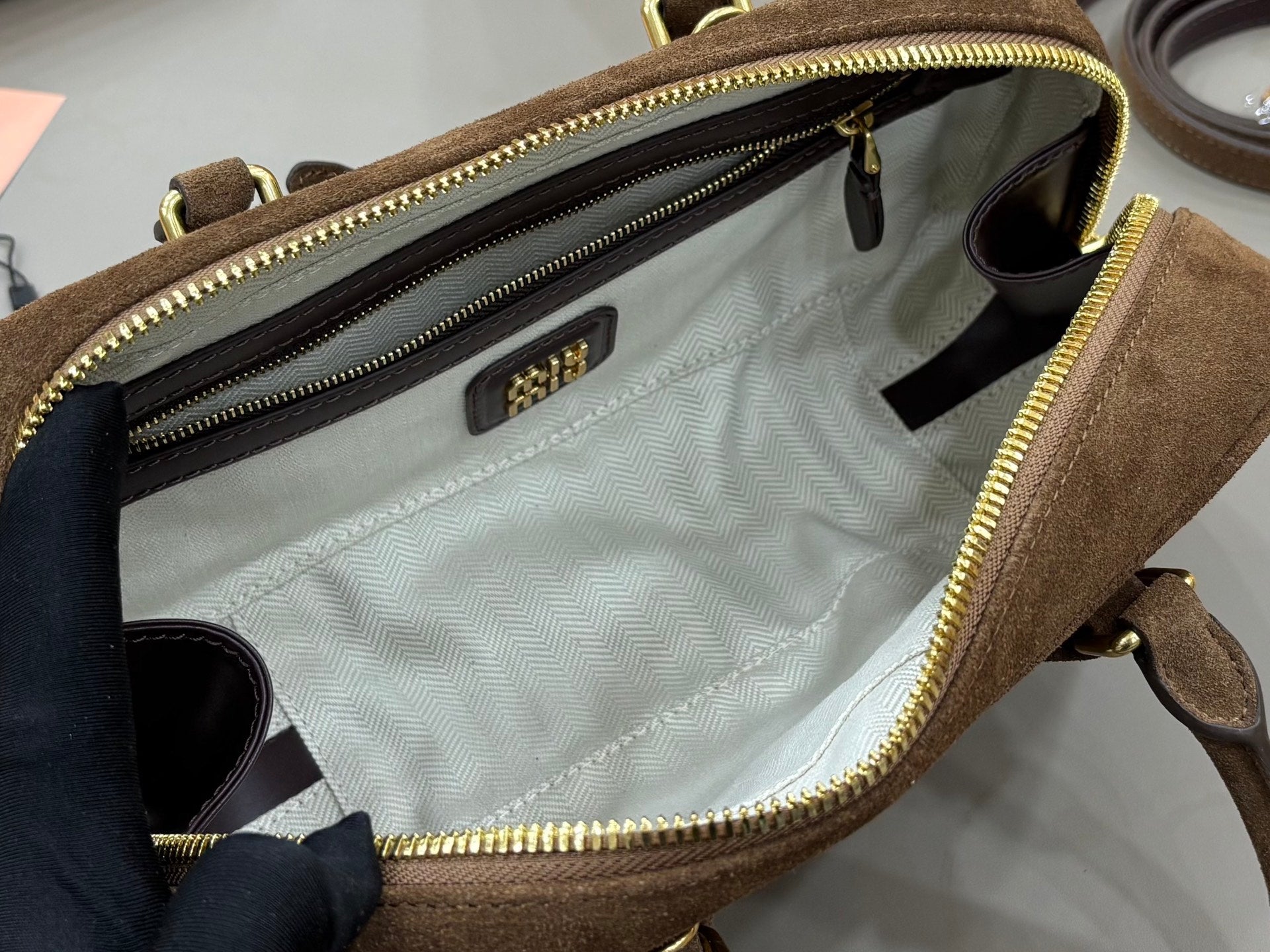 Open suede mini bag interior with chevron lining, multiple zip compartments, and label