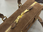 Front zipper detail on suede mini bag with gold-tone pull and side logo emblem