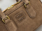 Suede mini handbag close-up of embossed miumiu logo and front pocket tabs