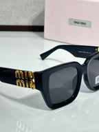 Dark navy square sunglasses with black lenses and gold “miu miu” logo on the temple