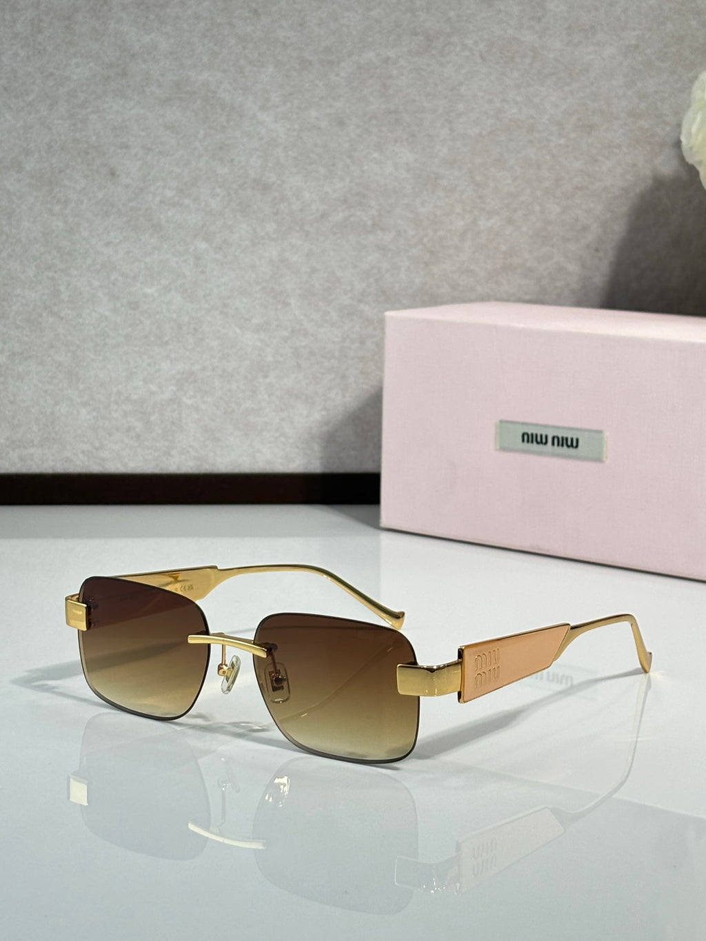 Gold-tone sunglasses with brown gradient lenses and logo on the temple arms