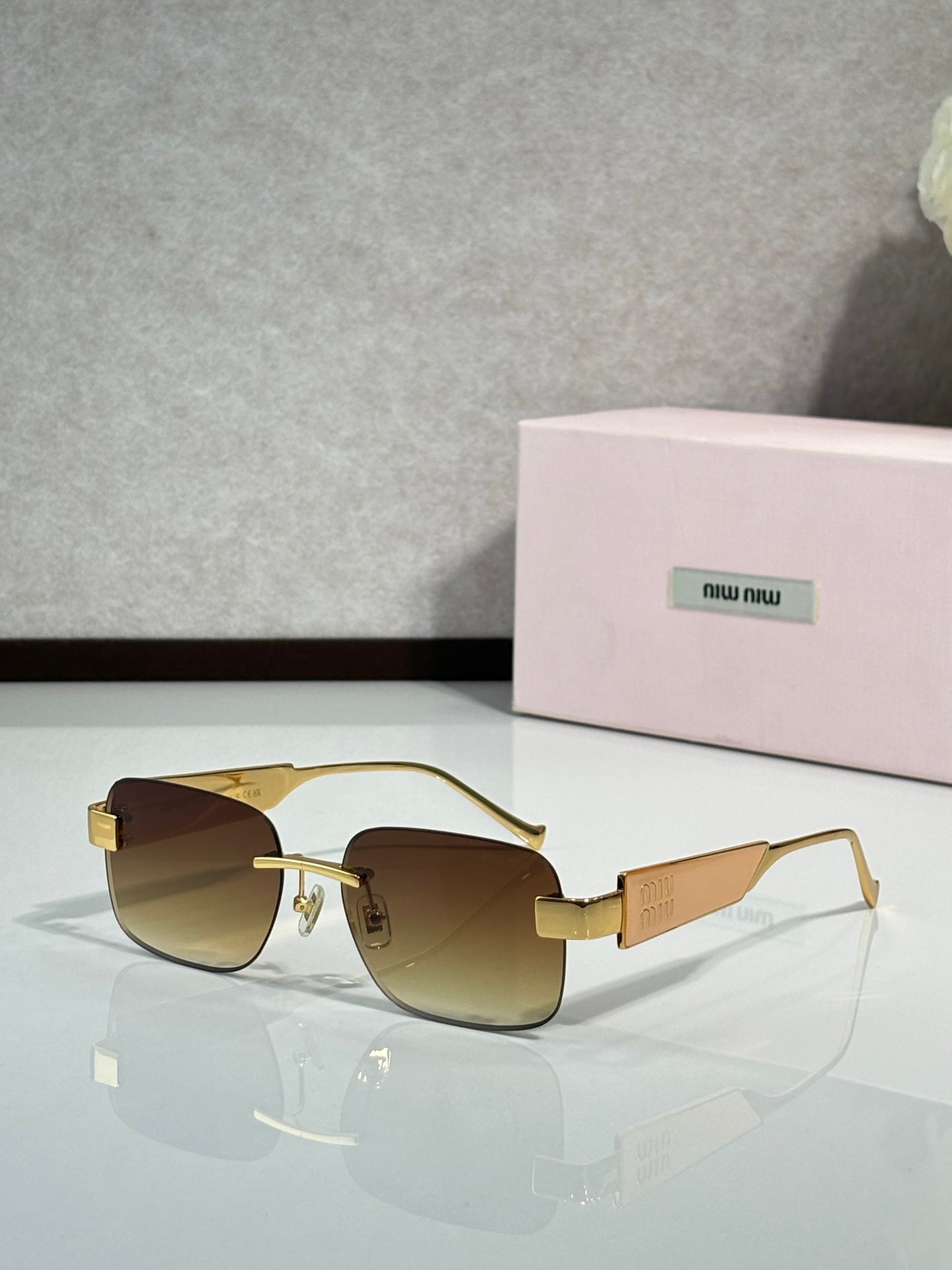 Gold-tone sunglasses with brown gradient lenses and logo on the temple arms