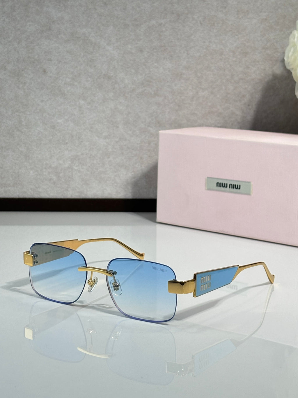 Gold-tone sunglasses with blue-tinted lenses and logo temple accents