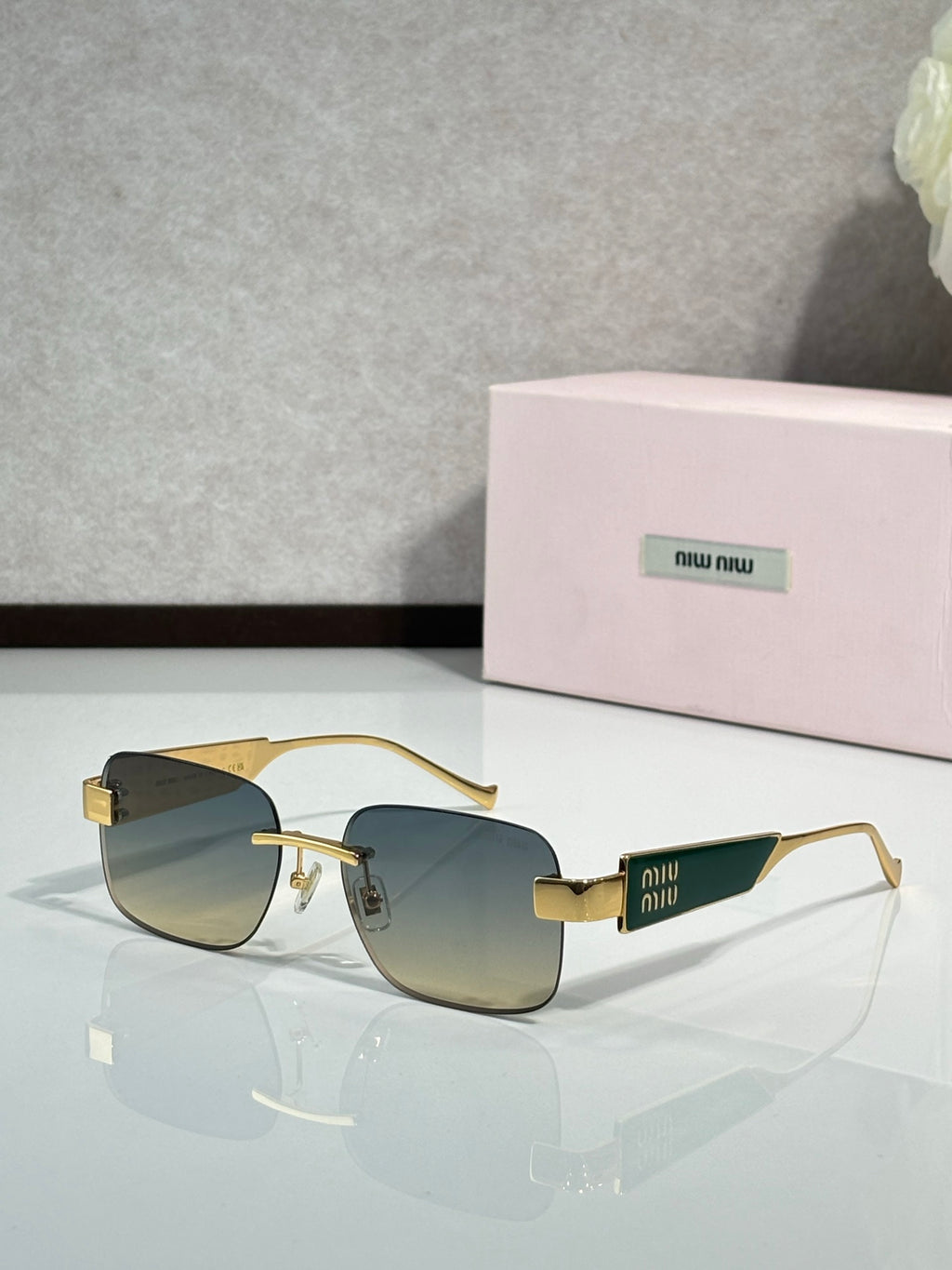 Gold-tone sunglasses with dark gradient lenses and Miu Miu logo on the temples