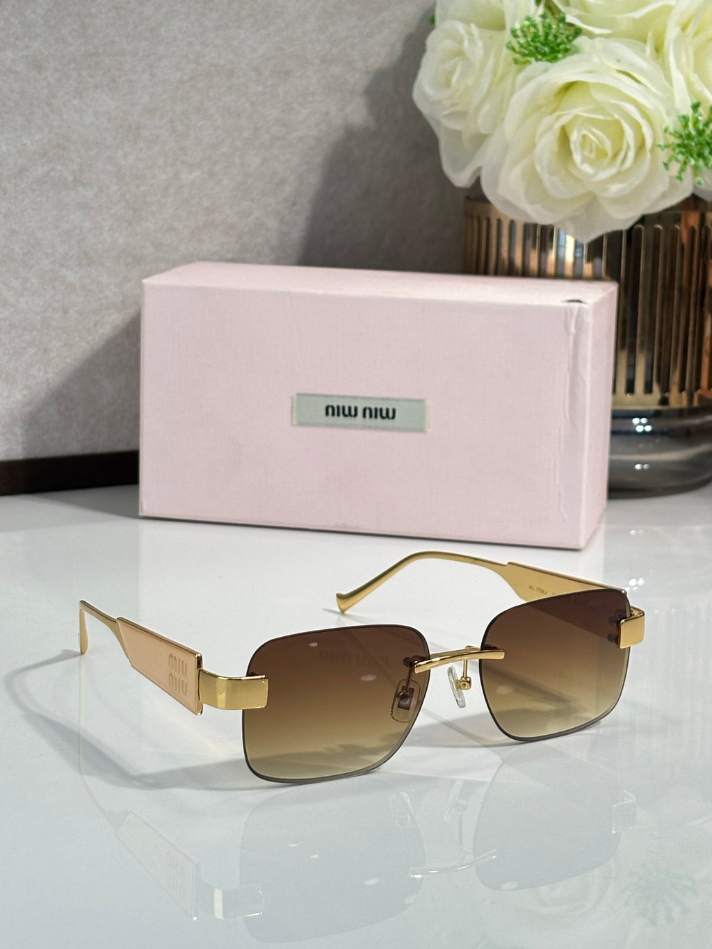 Gold-tone sunglasses with amber lenses and logo on the temple arms