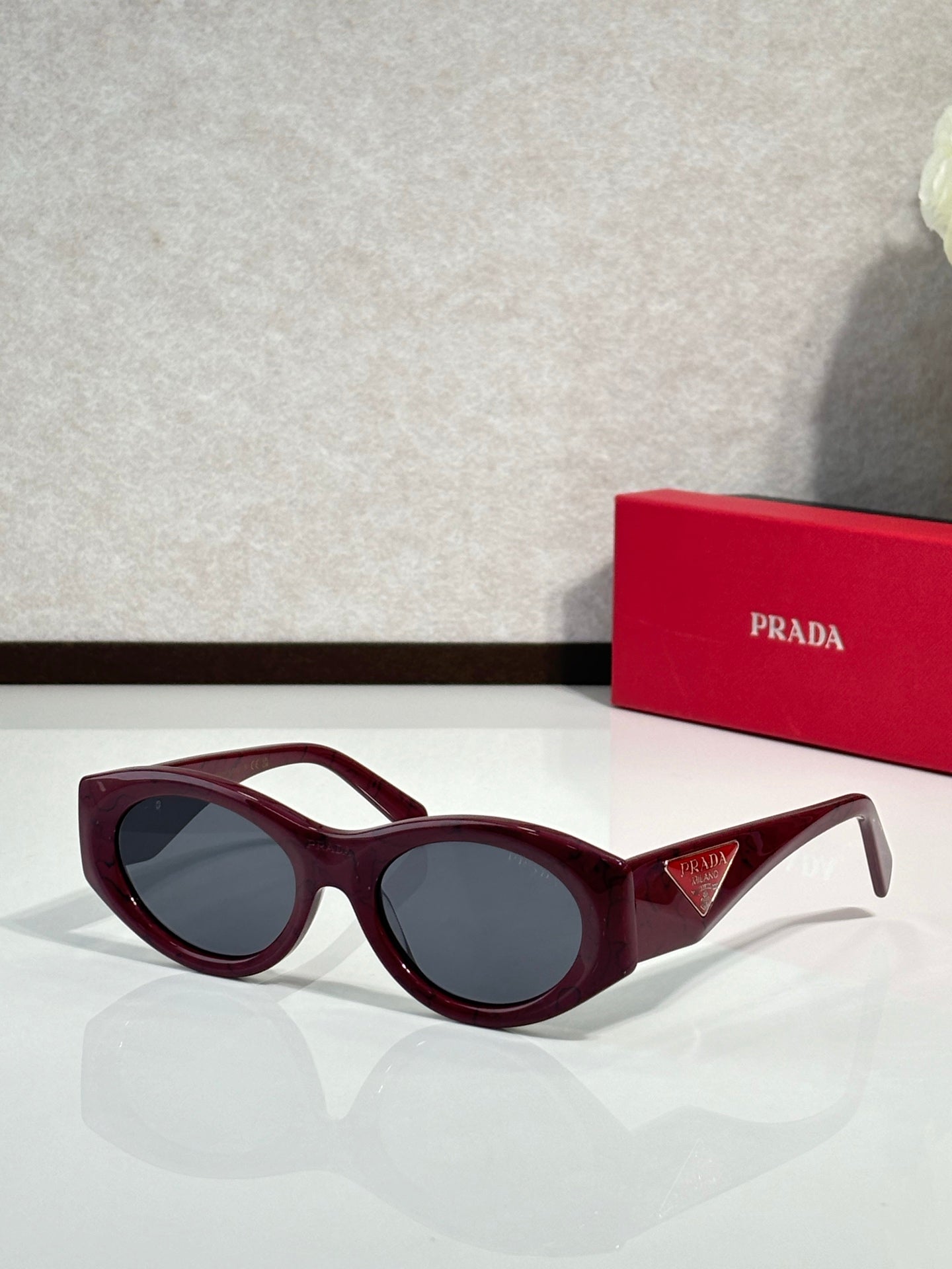 Prada burgundy cat-eye sunglasses with dark lenses and sculpted temples