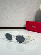 Prada patterned white sunglasses with dark lenses and rounded cat-eye shape
