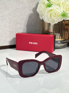 Prada dark burgundy sunglasses with dark lenses and glossy curved frame