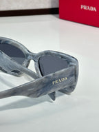 Prada gray marbled sunglasses with dark lenses and curved, angular frame