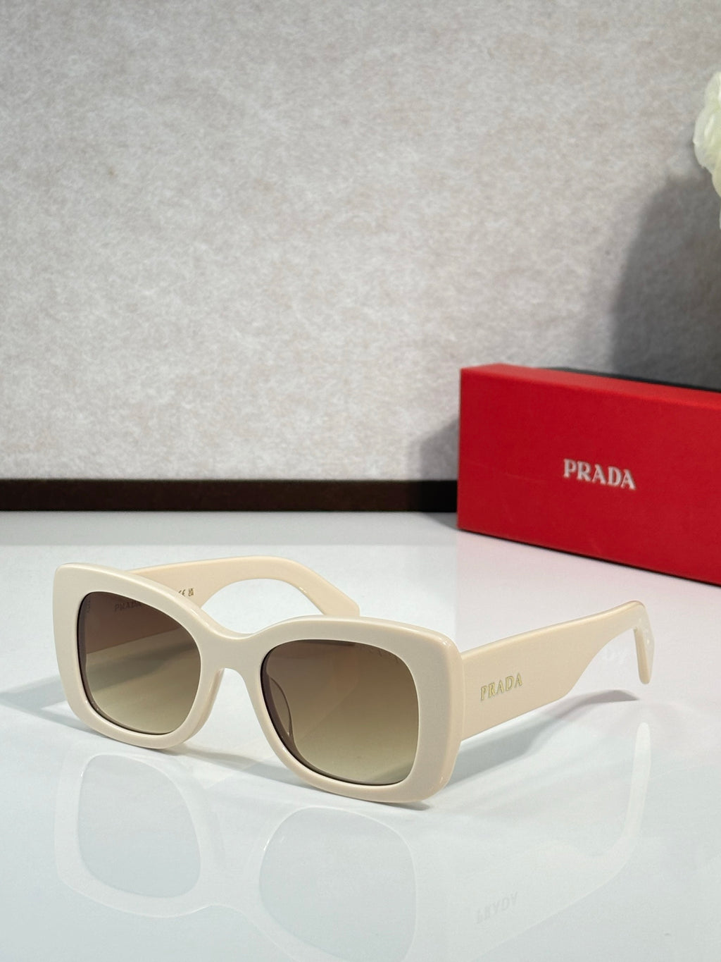 Prada cream sunglasses with dark lenses and curved cat-eye frame