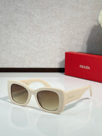 Prada cream sunglasses with dark lenses and curved cat-eye frame