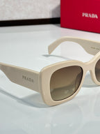 Prada cream sunglasses side view with dark-tinted lenses and curved frame