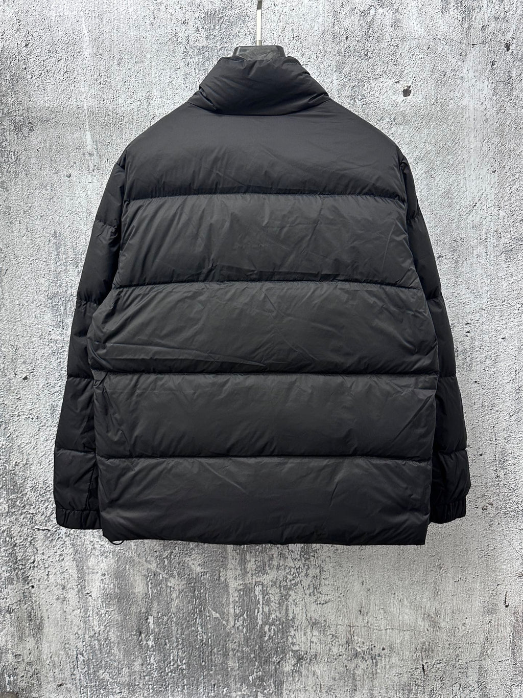 Long puffer jacket back view in dark color with standing collar