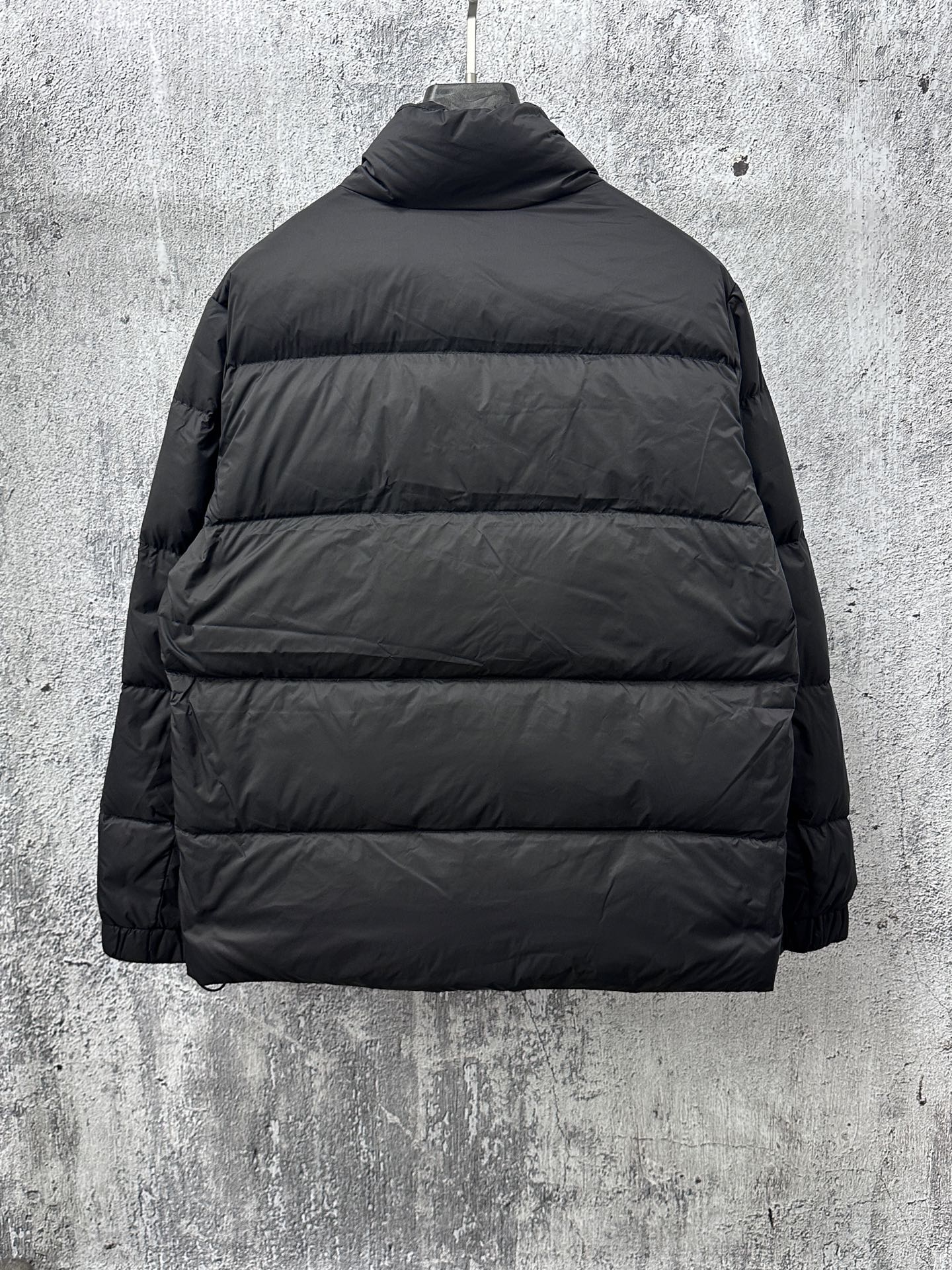 Long puffer jacket back view in dark color with standing collar