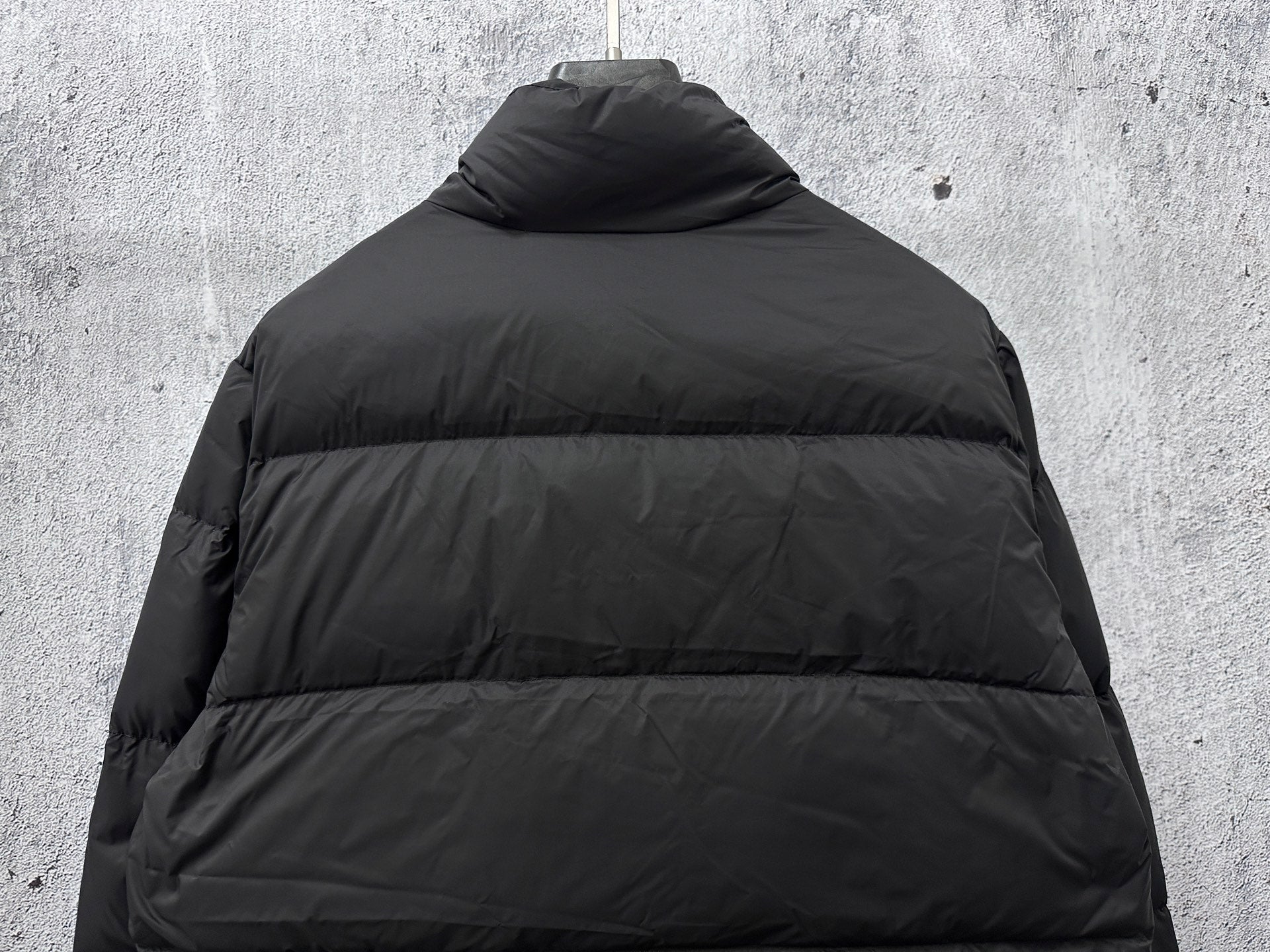 Long puffer jacket back view in dark color with raised collar
