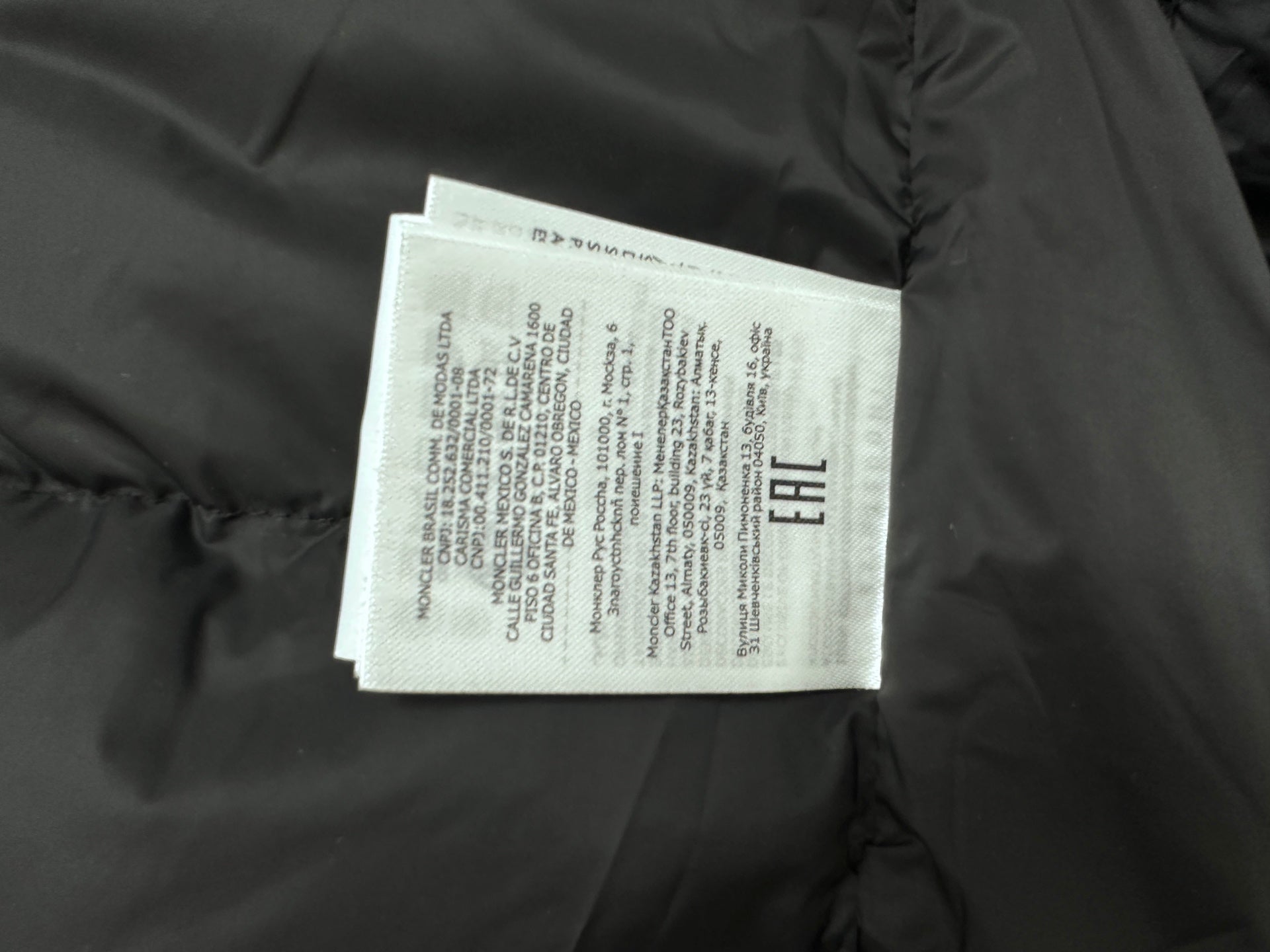 Long puffer jacket interior label tag on dark fabric
