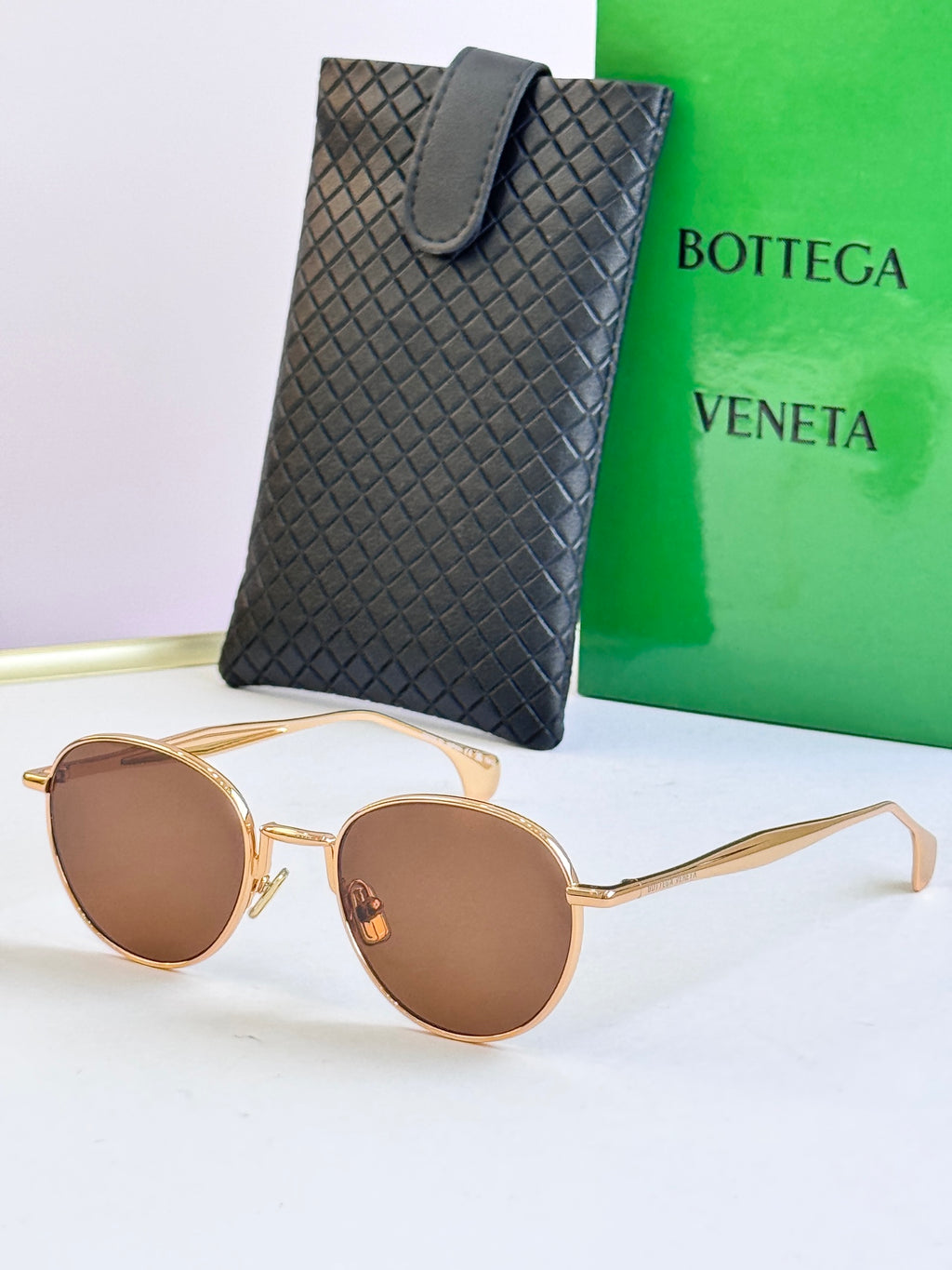 Round sunglasses with gold frame and dark brown lenses, with black leather case