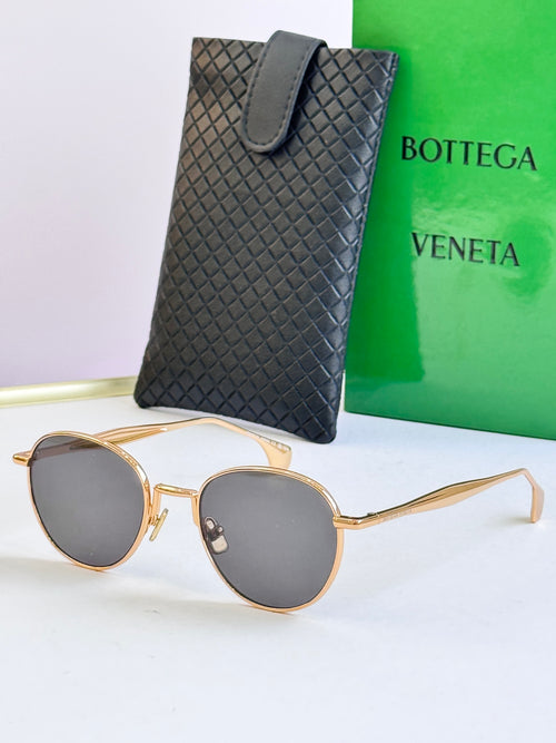 Round sunglasses with gold frame and dark gray lenses, with black leather case
