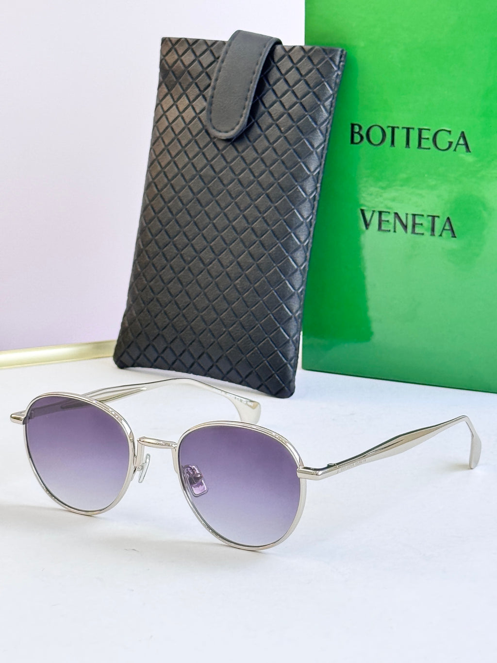 Round sunglasses with silver frame and light purple lenses, with black leather case
