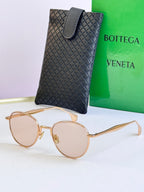 Round sunglasses with gold frame and light pink lenses, with black leather case