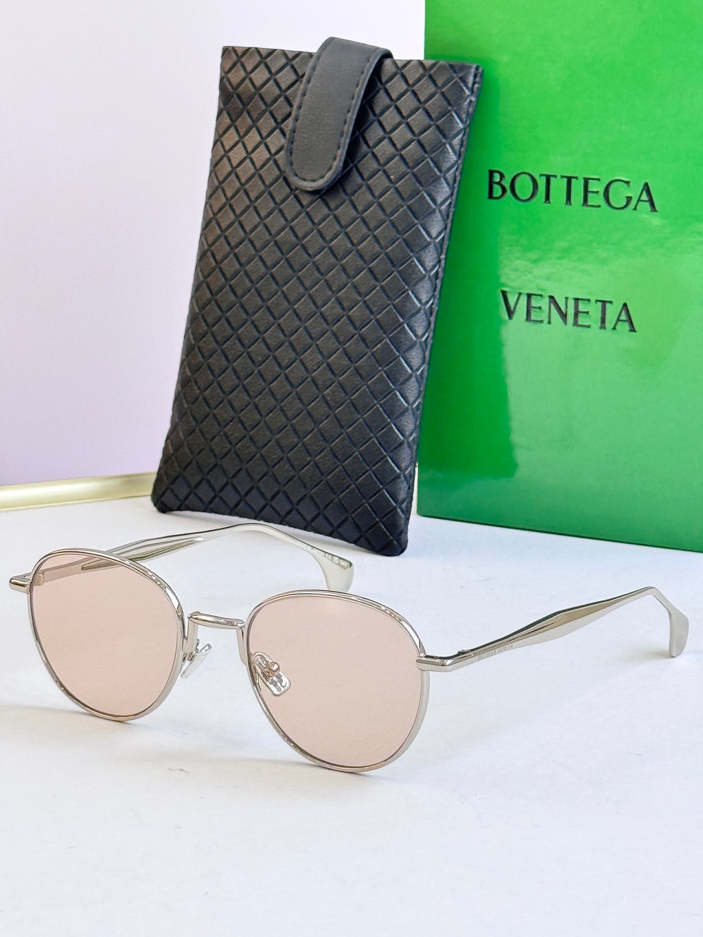 Round sunglasses with silver frame and light beige lenses, with black leather case