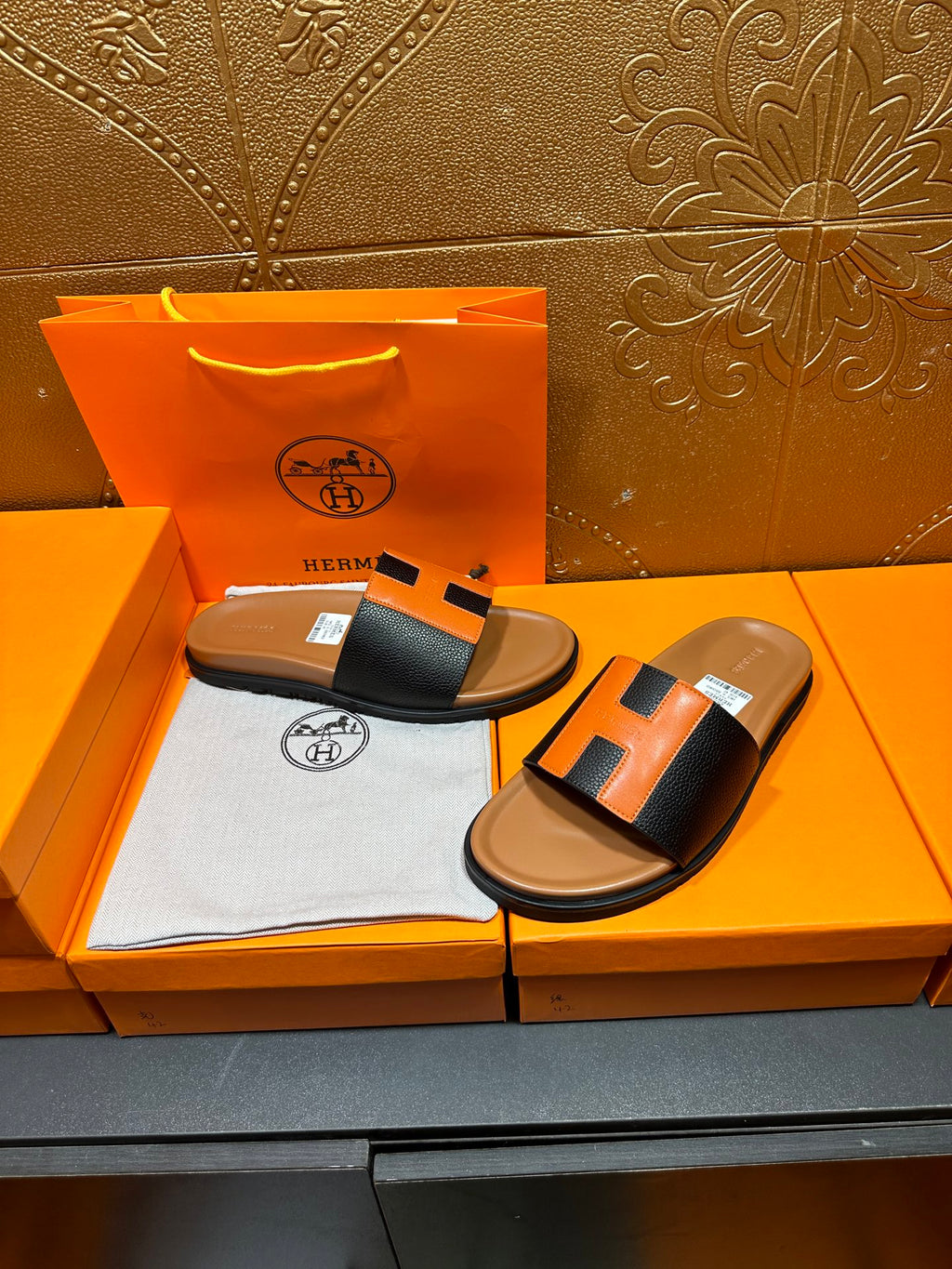Hermes slide sandals, black strap with orange H buckle, tan footbed pair