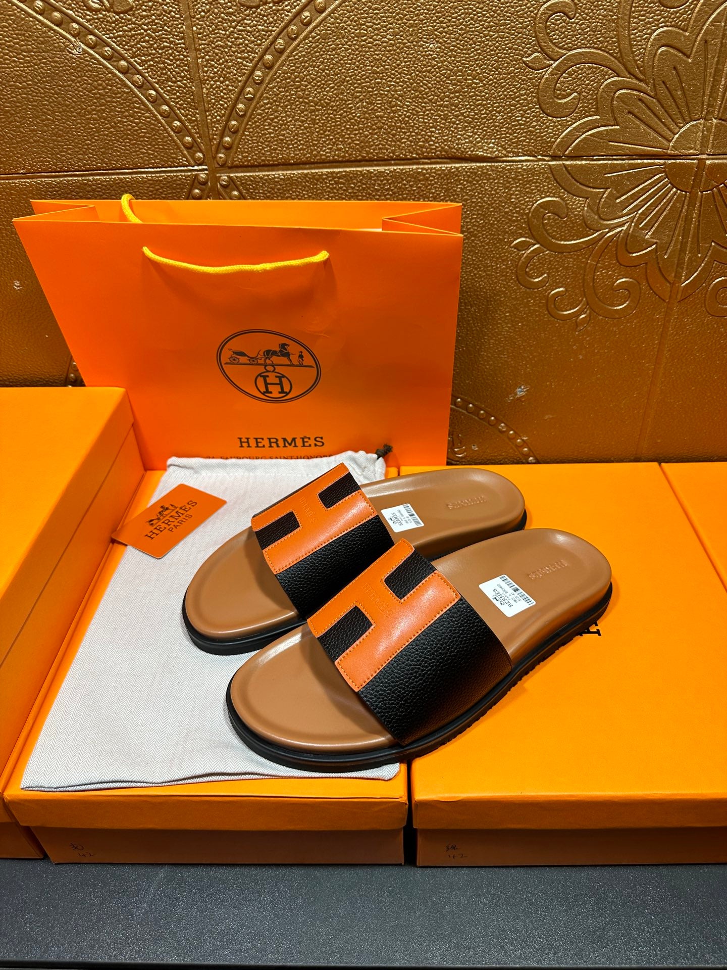 Hermes slide sandals, black strap with orange center H shape, tan cushioned footbed