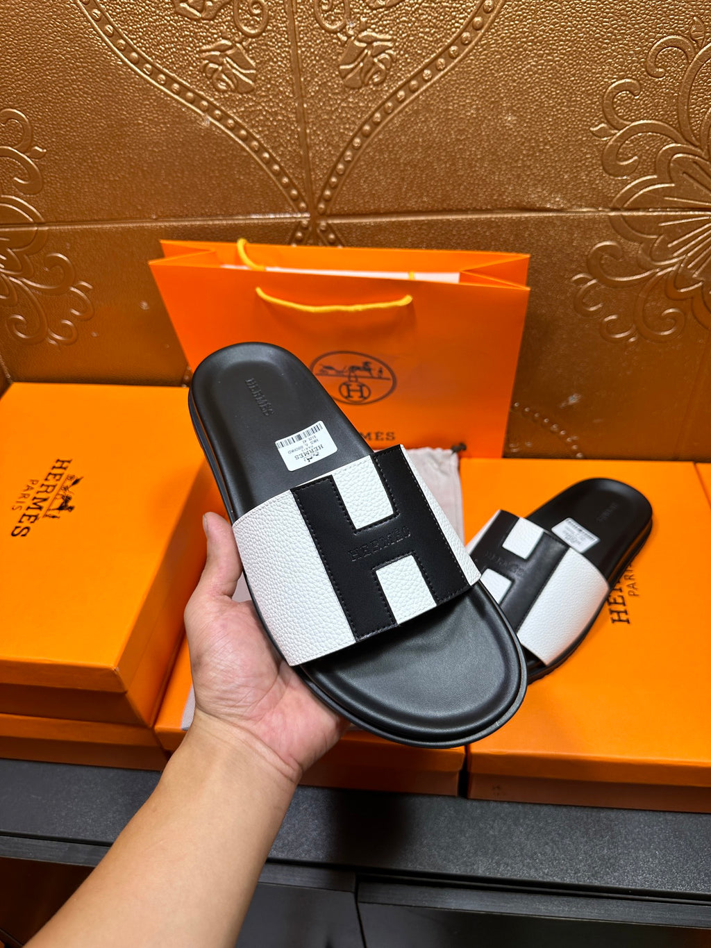 Hermes slide sandal held in hand, black sole with white strap and black insets