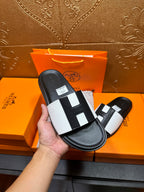 Hermes slide sandal held in hand, black sole with white strap and black insets